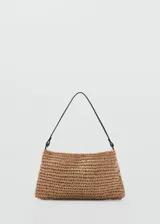 Bolso tipo cartera de mano de fibras naturales trenzadas en color tostado, de tamaño pequeño, con asa de hombro delgada de color negro y cierre magnético interior.