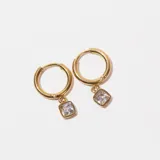 Aros tipo argolla dorados con dije cuadrado con piedra blanca.