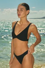 Bikini de dos piezas color negro confeccionada en lycra texturada. El corpiño es de estilo triángulo fijo con elástico interno bajo el busto para mayor ajuste. La bombacha es de corte vedetina con elástico interno y forrería al tono.
