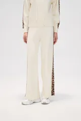 Pantalon de tejido de punto color crema, de corte ancho y tiro alto. Presenta una franja lateral con estampado animal print a lo largo de ambas piernas.