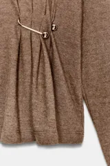 Top de cuello alto y manga larga, confeccionado en tejido de algodón gris melange. Presenta un diseño con frunces laterales ajustados mediante un aplique metálico decorativo.