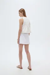 Minifalda de jean blanca de corte recto, con botonera frontal con botones metálicos dorados y costuras pespunteadas a contratono.