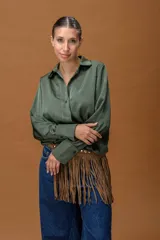 Camisa de seda color verde oliva, con cuello clásico, cierre frontal de botones y mangas largas con puños estructurados. Presenta un diseño con cintura elástica que genera un efecto blusado.