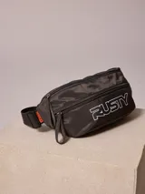 Riñonera de nylon color gris oscuro con cierre frontal y logo de la marca estampado en blanco. Cuenta con correa ajustable y etiqueta lateral con el nombre de la marca.