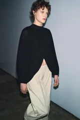 Top corto negro de punto fino, con cuello redondo y mangas largas abullonadas con pliegues.