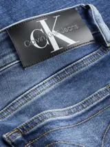 Pantalón de jean azul de corte slim fit, tiro bajo, con lavado vintage y diseño de cinco bolsillos.