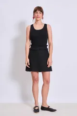 Minifalda de color negro con detalle de volados en la cintura y corte recto.