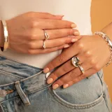 Anillo de plata 925 con diseño de piedra central grande y brillante, con banda decorada con pequeños cristales.