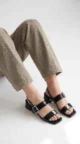 Sandalia de cuero color beige con taco cuadrado de 4 cm, tiras delanteras, tira ajustable con hebilla metálica dorada y tira elástica trasera.