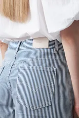 Bermuda de denim azul claro con rayas verticales blancas, de corte relajado y largo hasta la rodilla. Presenta pespuntes a contratono.