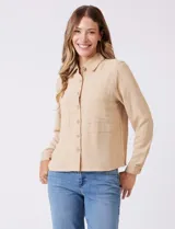 Camisa de crepe color beige con cuello clásico, cierre frontal con botones y dos bolsillos aplicados en el pecho.