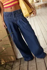 Pantalón wide leg de tiro medio confeccionado en denim, con cintura trabajada con pasacintas entrelazadas, cierre frontal y bolsillos laterales.