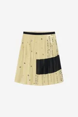 Falda de tiro medio confeccionada en hilatura de lino, color beige con bloques negros y detalles de abalorios y ojales metálicos aplicados a contraste. Cuenta con cierre lateral con cremallera oculta en costura.