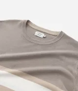 Suéter de punto con cuello redondo y manga larga, diseñado con un patrón de bloques de color en tonos beige, blanco y gris. Presenta un corte regular que se ajusta de forma anatómica al cuerpo.
