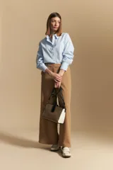 Pantalón ancho color tostado, de silueta fluida y cintura elastizada. Presenta una pretina ancha con botones metalizados irregulares.