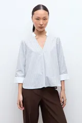Blusa rayada en tonos beige y celeste, con cuello mao, escote en V y mangas 3/4 con puños blancos.