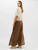 Blusa de algodón semitransparente con diseño floral bordado a tono. Presenta escote en V, cierre frontal con botones y mangas al codo ligeramente abullonadas. Incluye detalles de encaje calado estilo macramé en los puños y en el ruedo con terminaciones en ondas.