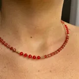 Gargantilla corta de cuentas facetadas rojas y doradas.