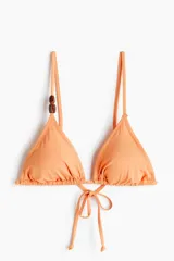 Top de bikini de triángulo color salmón con tiras finas ajustables para atar en la espalda y detalle de cuentas carey en el bretel derecho. Cuenta con copas con relleno extraíble y diseño forrado.