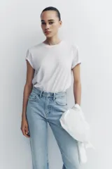 Jeans de tiro alto color negro con efecto lavado, corte mom fit, cinco bolsillos y cierre frontal con cremallera y botón metálico.