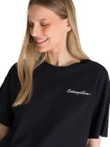 Remera negra de corte boxy y diseño liso, con cuello redondo y mangas cortas. Cuenta con un pequeño logo bordado en contraste sobre el pecho y parche bordado en la manga.