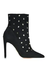 Botineta negra de gamuza con punta fina, taco aguja y apliques de tachas doradas.