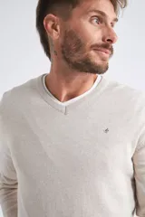 Sweater de tejido de punto color beige, con escote en V, mangas largas y puños y dobladillo acanalados. Presenta un pequeño logo bordado en el pecho.