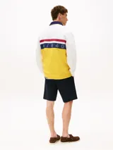 Chomba de rugby Tommy Hilfiger Sailing, unisex, de corte amplio y hombros caídos. Diseño color block blanco, amarillo y azul, con logo de la marca bordado en el pecho.