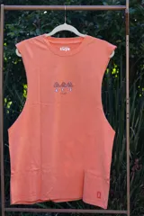 Musculosa de algodón premium color naranja con efecto lavado, corte ancho y sin mangas. Presenta un estampado central de tres hongos estilizados y texto.