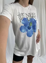 Remerón blanco de corte holgado con estampa de hibisco azul y texto en negro.
