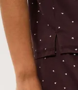 Blusa de pijama de manga corta y cuello redondo, de color marrón oscuro con estampado integral de pequeños corazones blancos. Confeccionada en tejido peach touch de poliéster y elastano.