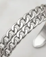 Pulsera esclava de acero con diseño de doble cadena de eslabones entrelazados.