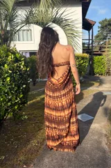 Vestido largo strapless, ajustado al cuerpo, con estampado batik en tonos marrones y naranjas.