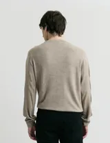 Sweater de tejido de punto con escote redondo y manga larga. Presenta un diseño clásico con detalles de terminación en sisas y cuello.