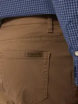 Pantalón de corte recto en color tostado, confeccionado en tejido de algodón con elastano. Presenta cierre frontal con botón y cremallera, además de bolsillos laterales y traseros.