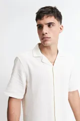 Camisa de manga corta color crema con textura, cuello clásico y calce regular.