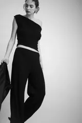 Pantalón de punto color negro con efecto arrugado, tiro alto, cintura elástica y piernas amplias.