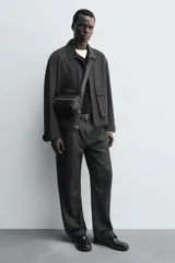 Bandolera negra con textura grabada, compartimento principal con cierre de cremallera, bolsillo interior con cremallera, bolsillo frontal con cremallera y asa de hombro ajustable.