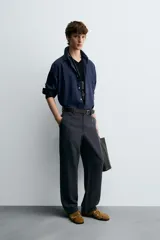 Pantalón de vestir negro, corte recto y relajado, con cintura elástica, cierre frontal con cremallera y botón, bolsillos delanteros y bolsillos traseros de plastrón.