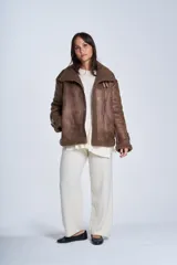 Campera gamulán marrón de símil cuero, con interior de corderoy al tono, cierre frontal con cremallera y cuello con solapas grandes. Presenta detalles de hebillas en los puños y bolsillos laterales con cierre.