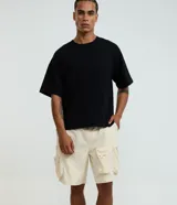Bermuda baggy cropped de color beige, confeccionada en poliéster, con bolsillos cargo laterales y cintura elástica.