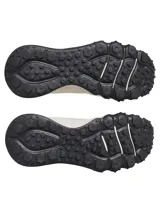 Championes de trail running Under Armour modelo Charged Maven, color beige con detalles en negro y logo celeste. Presentan una parte superior de malla técnica transpirable con refuerzos de poliuretano, entresuela Charged Cushioning para mayor amortiguación y suela de goma con tacos multidireccionales para un agarre óptimo en terrenos irregulares.