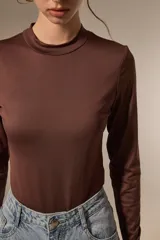 Body de manga larga con cuello a la base, confeccionado en poliamida, con ajuste al cuerpo y cierre inferior con broches.