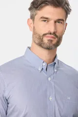 Camisa de vestir celeste con finas rayas verticales blancas, de corte clásico, con cuello abotonado y bolsillo en el pecho.