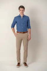 Pantalón de corte slim fit en color beige, confeccionado en algodón, con cierre frontal de botón y cremallera, y bolsillos laterales.