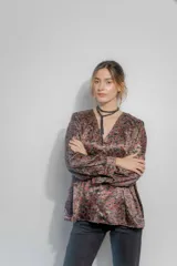 Camisa de seda con estampado floral en tonos bordó, marrón y negro. Presenta un corte amplio, escote en V con cierre frontal de botones, mangas largas abullonadas y frunces en hombros y espalda.