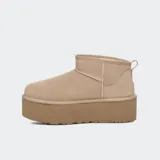 Botas de caña baja tipo botineta con plataforma elevada, confeccionadas en gamuza color marrón. Presentan costuras con detalle de puntada overlock, lengüeta trasera y forro interior de lana suave.