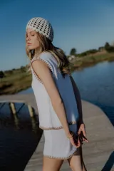 Conjunto de dos piezas tejido en algodón, compuesto por un chaleco sin mangas con cierre frontal de botones y un short de tiro medio. Ambas prendas presentan un diseño en color blanco con detalles de terminaciones en color beige.