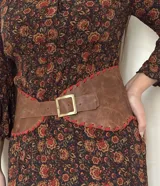 Faja de cuero vacuno marrón con costuras artesanales en tiento de gamuza roja y hebilla metálica dorada.