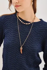 Sweater de punto color verde con diseño de ondas en relieve y sutiles destellos de lentejuelas integradas. Presenta cuello redondo, mangas largas y puños acanalados.